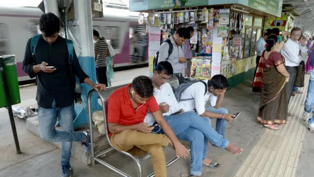 బస్ ‌స్టాప్‌లో మొబైల్ చూస్తున్నప్రజలు
