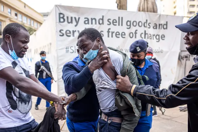 Kenyan police officers arrest protesters during a march
