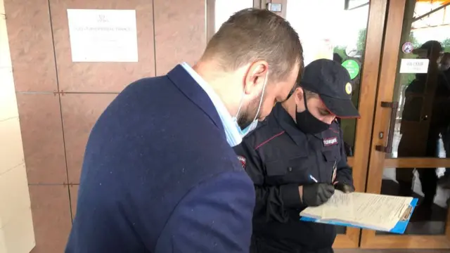 Полицейский выписывает повестку одному из участников съезда
