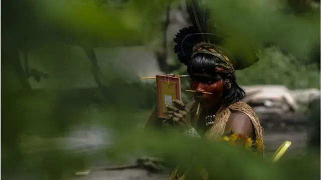 An indigenous man prepares himself as Indigenous people of various ethnicities meet on the occasion of the International Day of Indigenous Peoples, at Aldeia Maracana, north of the Rio de Janeiro, Brazil, Aug 2022