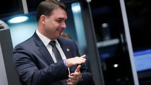 No Senado, Flávio Bolsonaro aparece sorrindo e olhando para o lado