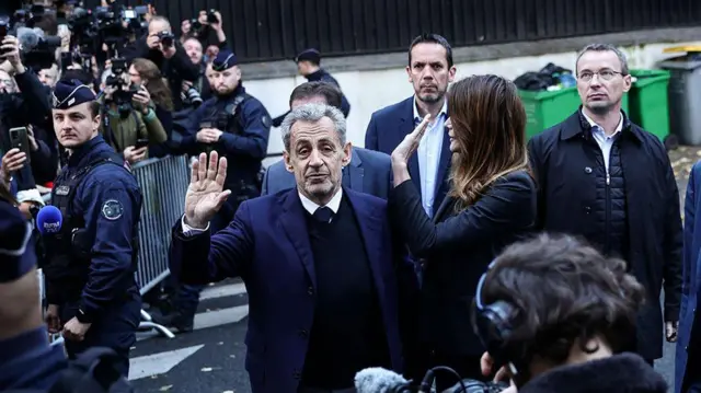 Former French President Nicolas Sarkozy and im wife wave give di crowd and photographers for di street bifor e enta prison