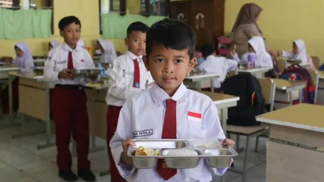 Siswa menerima porsi makan bergizi gratis pada hari pertama di SD Negeri Kedung Badag 1 Bogor, Jawa Barat, pada 6 Januari 2025.