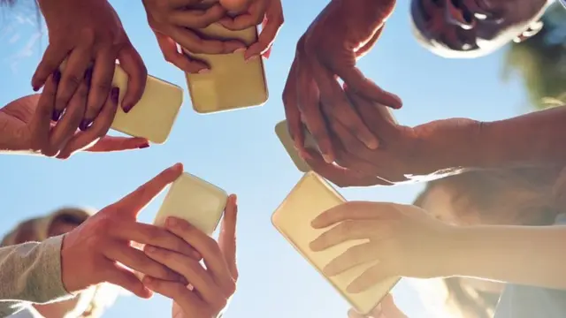 Un círculo de jóvenes mirando sus teléfonos celulares