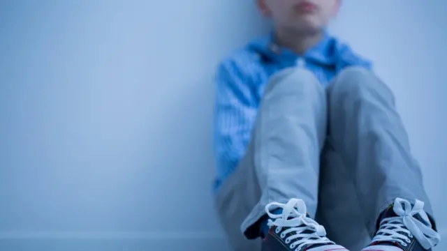 Un niño sentado en el suelo con gesto serio (imagen difuminada(