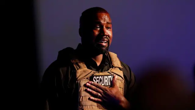 Kanye en pleure avec la main sur la poitrine.