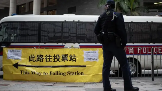 A police officer stands guard near a polling station in Hong Kong, 19 December 2021