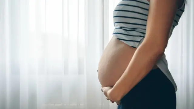 Mujer embarazada frente a la ventana.