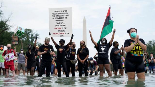 Protesters hold signs from inside the Lincoln Memorial Reflecting pool during the 2020 March on Washington