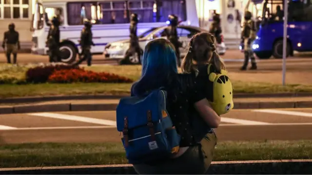 Женщина с ребенком наблюдают за акцией протеста в Минске 10 августа