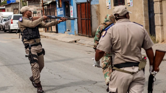 A police officer firing rubber bullets in Alexandra, South Africa - Tuesday 31 March 2020