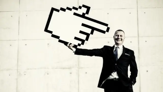 Un hombre que sujeta un signo gigante parecido al "me gusta", y que apunta hacia sí mismo