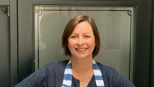 A chef Carla Pernambuco sorrindo para a foto e usando um avental