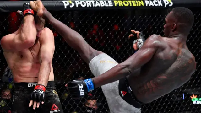 Israel Adesanya of Nigeria (R) kicks Jan Blachowicz (L) of Poland in their UFC light heavyweight championship fight during the UFC 259 event at UFC APEX in Las Vegas, Nevada - Saturday 6 March 2021