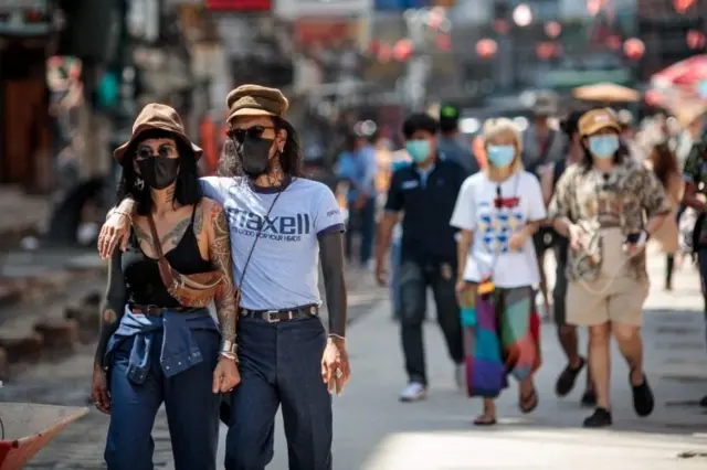 Tourists wearing facemasks amid concerns over the spread of the COVID-19 novel coronavirus walk along Khao San Road, a popular area for tourists in Bangkok on March 6, 2020
