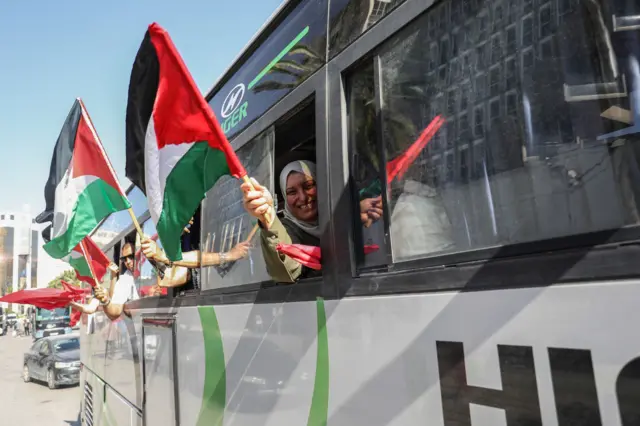 ركاب حافلة ضمن القافلة يلوحون بالعلم الفلسطيني من النوافذ