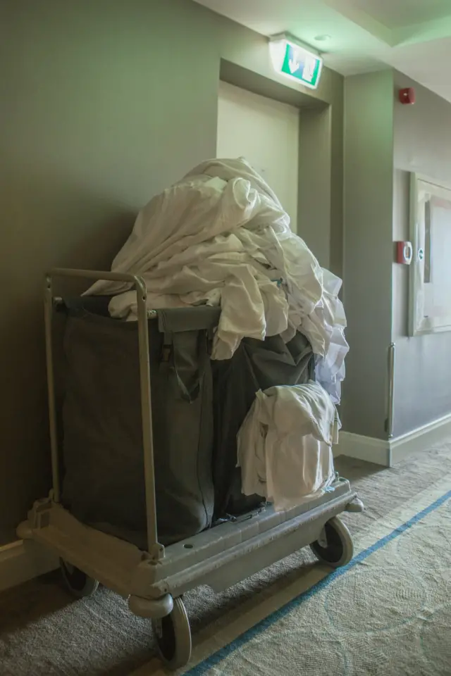 Carrito con toallas sucias apiladas en el corredor de un hotel