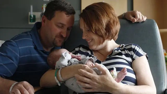 குழந்தையை கொஞ்சும் பெற்றோர்.