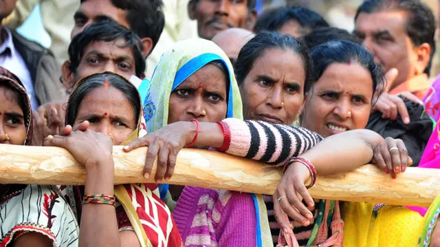 Mujeres haciendo fila frente a un banco en una zona rural