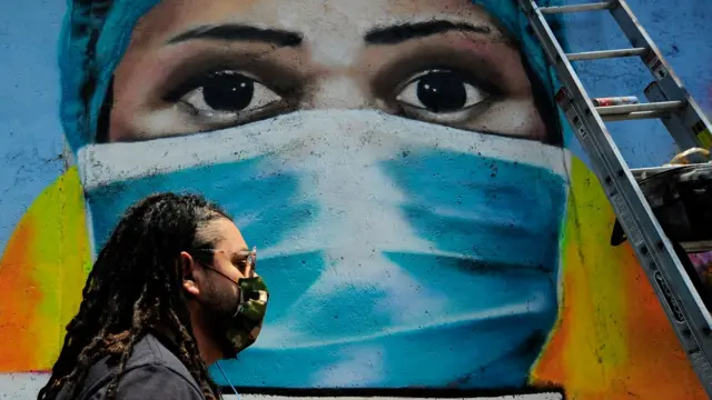 Un hombre camina delante de una pared con un mural