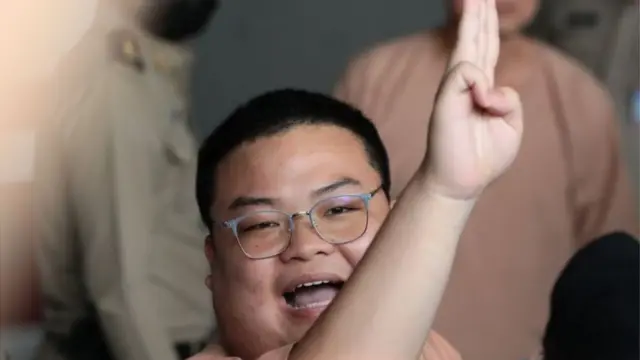 พริษฐ์ ชิวารักษ์ หรือ "เพนกวิน" 1 ใน 22 จำเลยคดีชุมนุม "19 กันยาทวงอำนาจคืนราษฎร" ชูสามนิ้วขณะที่เดินทางจากเรือนจำพิเศษกรุงเทพฯ มาถึงศาลอาญาวันนี้ (15 มี.ค.)