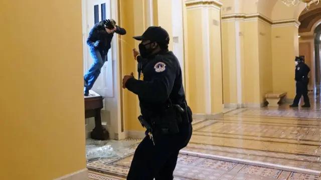 Um policial do Capitólio dos EUA atira spraynovibet 50 bônuspimentanovibet 50 bônusum protesto entrando no prédio por uma janela quebrada