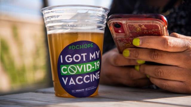 美國華盛頓某疫苗接種中心外一位接種完畢的女士在享用免費派發的啤酒（6/5/2021）