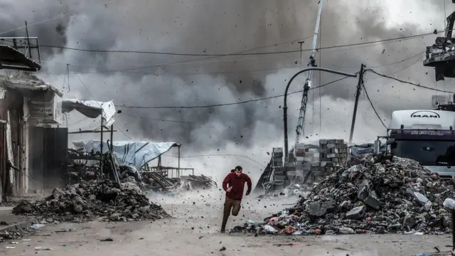 رجل يهرب من الأنقاض عقب الهجوم الإسرائيلي على مبنى من ثلاثة طوابق قرب تقاطع أسكولا في حي الزيتون، على الرغم من اتفاق وقف إطلاق النار في مدينة غزة، غزة، في 6 فبراير/شباط 2026.