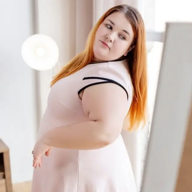 ایک موٹی خاتون خود کو آئینے میں دیکھتے ہوئے