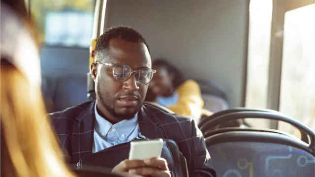 Un homme noir qui regarde son téléphone assis dans le bus