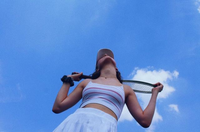 Una chica mira el cielo con su raqueta de tenis