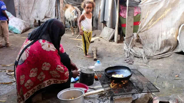 Seorang perempuan memasak di kamp sementara di Aden, Yaman pada 15 Maret.