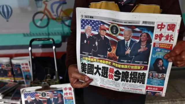 A man sells newspapers with front page articles about the US election along a street in Taipei