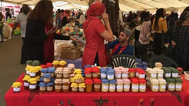 Des clients à l'assaut des produits africains. Du beurre de karité exposé sur une table.