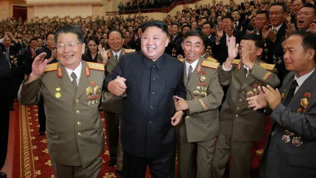 金正恩（中）在李洪燮（左）等军中干部簇拥下在平壤人民剧院内走动（朝中社2017年9月10日发放图片）