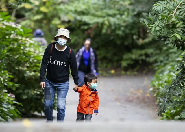Una familia en Vancouver caminando al aire libre con mascarillas puestas