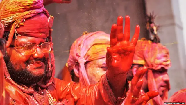 रंगों की बौछारों को रोकती मंद मुस्कान