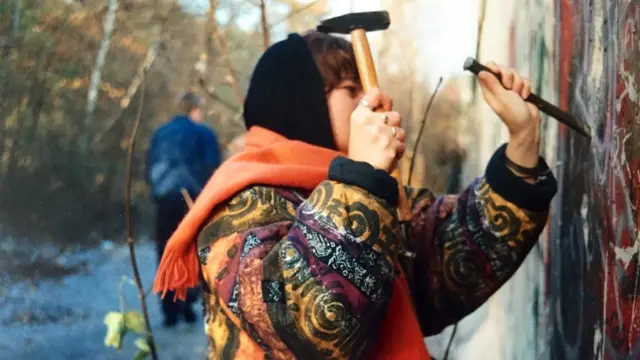 A woman trying to get a piece of the wall in West Berlin just days after it officially opened in November 1989