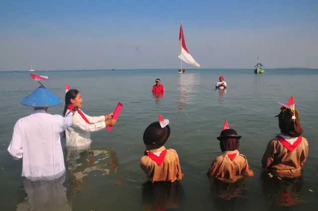 Petugas membacakan teks pembukaan UUD 1945 saat mengikuti upacara pengibaran bendera Merah Putih di Pantai Pelayaran, Desa Karangkebagusan, Jepara, Jawa Tengah, Sabtu (17/8/2024). 