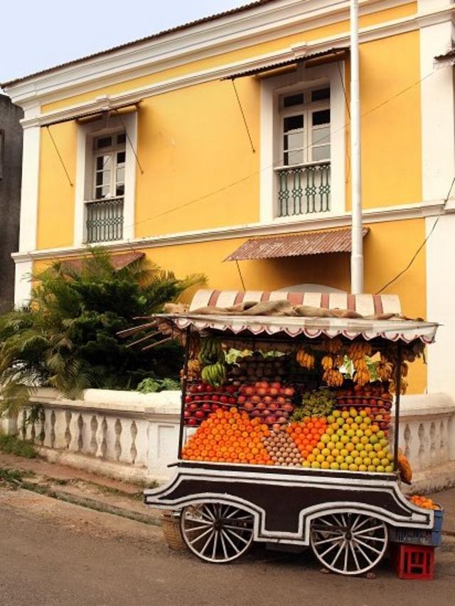 Casa colonial amarela perto de uma carrocinha vendendo mangas