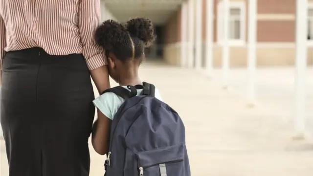 Una niña y su madre yendo a la escuela