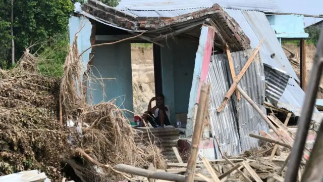 Un hombre está sentado en medio de sucasa destruida durante las fuertes lluvias en Katmandú, la capital de Nepal.