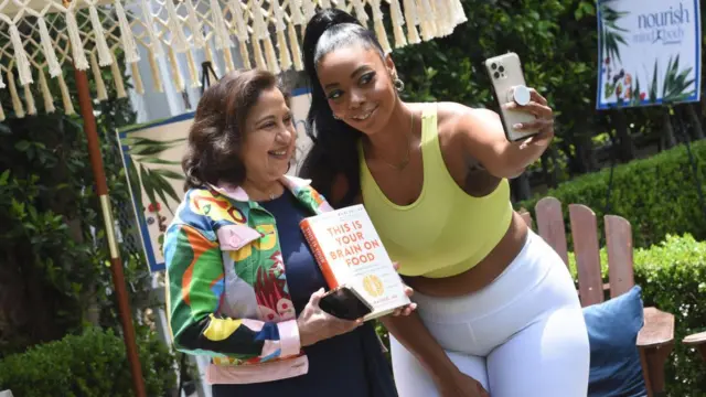 Uma Naidoo (segurando seu livro) e fã tiram selfie sorrindopoker javaáreapoker javajardim