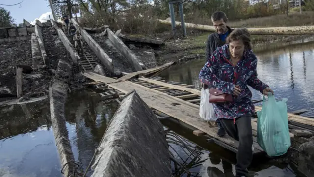 বাখমুতের একটি বিধ্বস্ত সেতু দিয়ে পার হচ্ছেন কিছু বেসামরিক মানুষ।