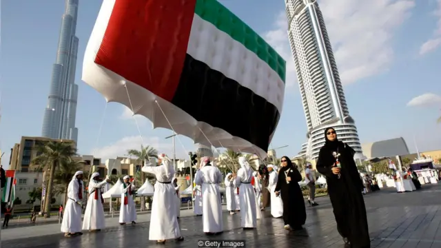 Hombres que llevan una bandera de EAU en una plaza