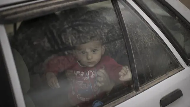 Criança olha pela janela de carro