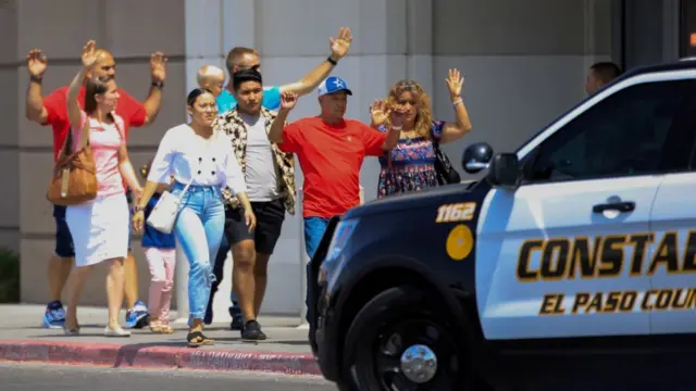 Compradores saliendo con las manos en alto de Walmart.