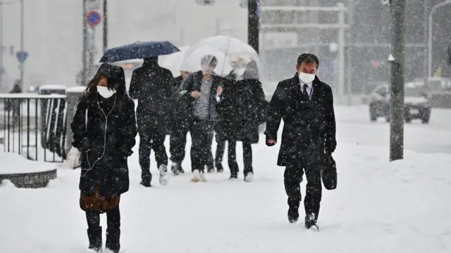 Pessoas com máscara andandorua do Japão, com neve