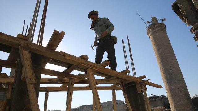 عامل عراقي ينصب حمالات خشبية