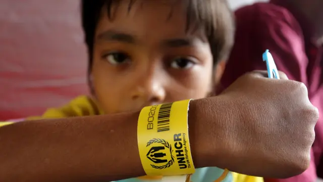Seorang anak imigran etnis Rohingya memperlihatkan gelang pengenal dari UNHCR saat berada di dalam tenda di kawasan komplek kantor Bupati Aceh Barat, Aceh, Rabu (27/03).